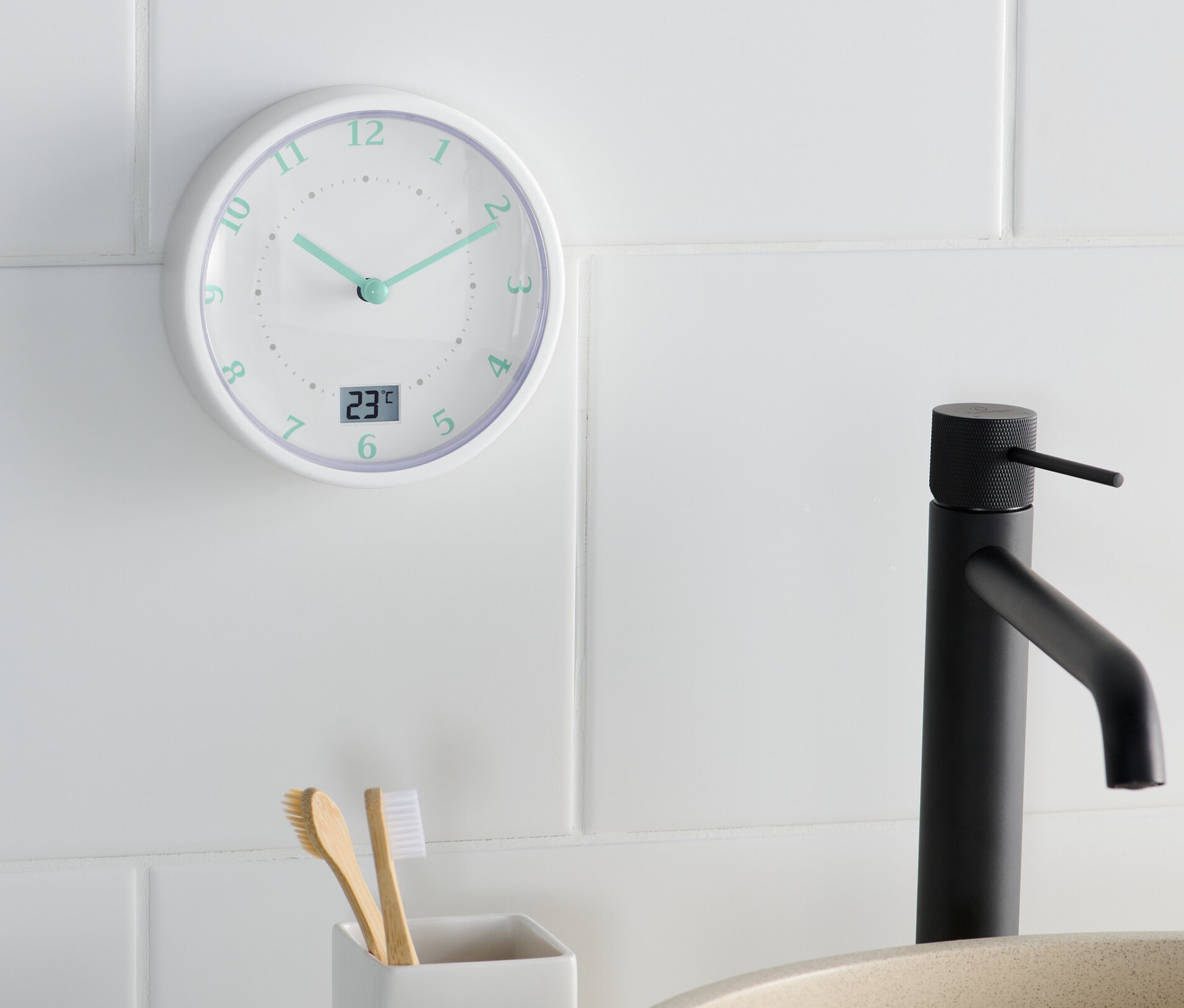 Une horloge murale de salle de bain indique 11h22 à côté d'un lavabo et d'un porte-brosses à dents.