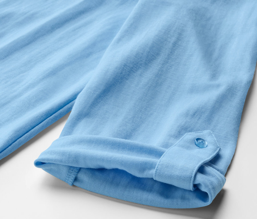 Gros plan sur une chemise en jersey piqué bleu clair avec une manche retroussée.