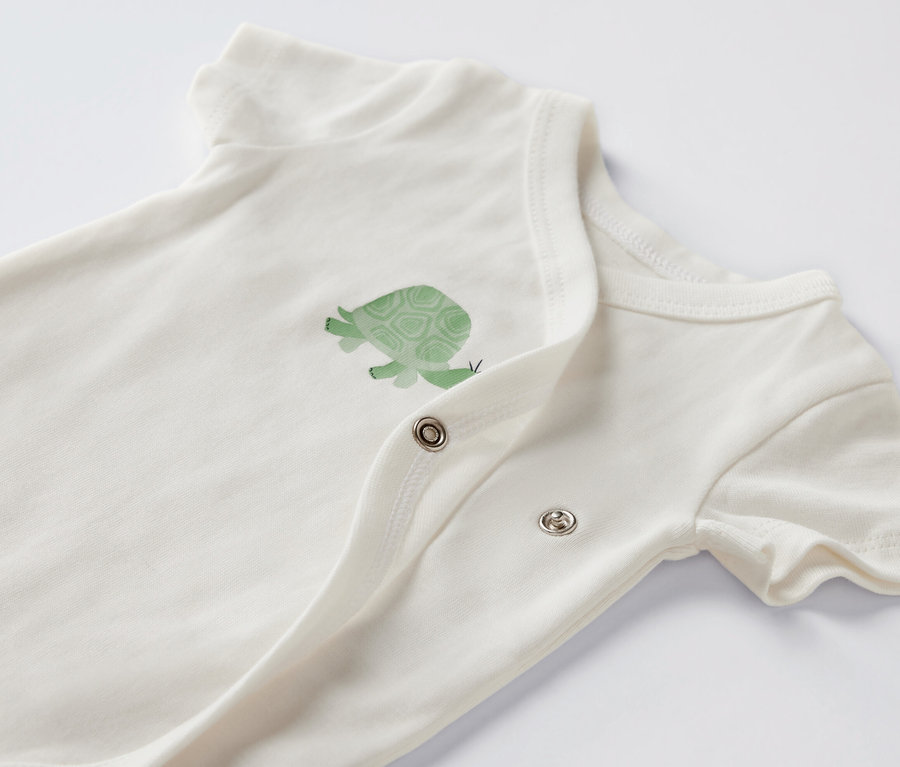 Gros plan sur un body blanc à manches courtes avec un motif de tortue.