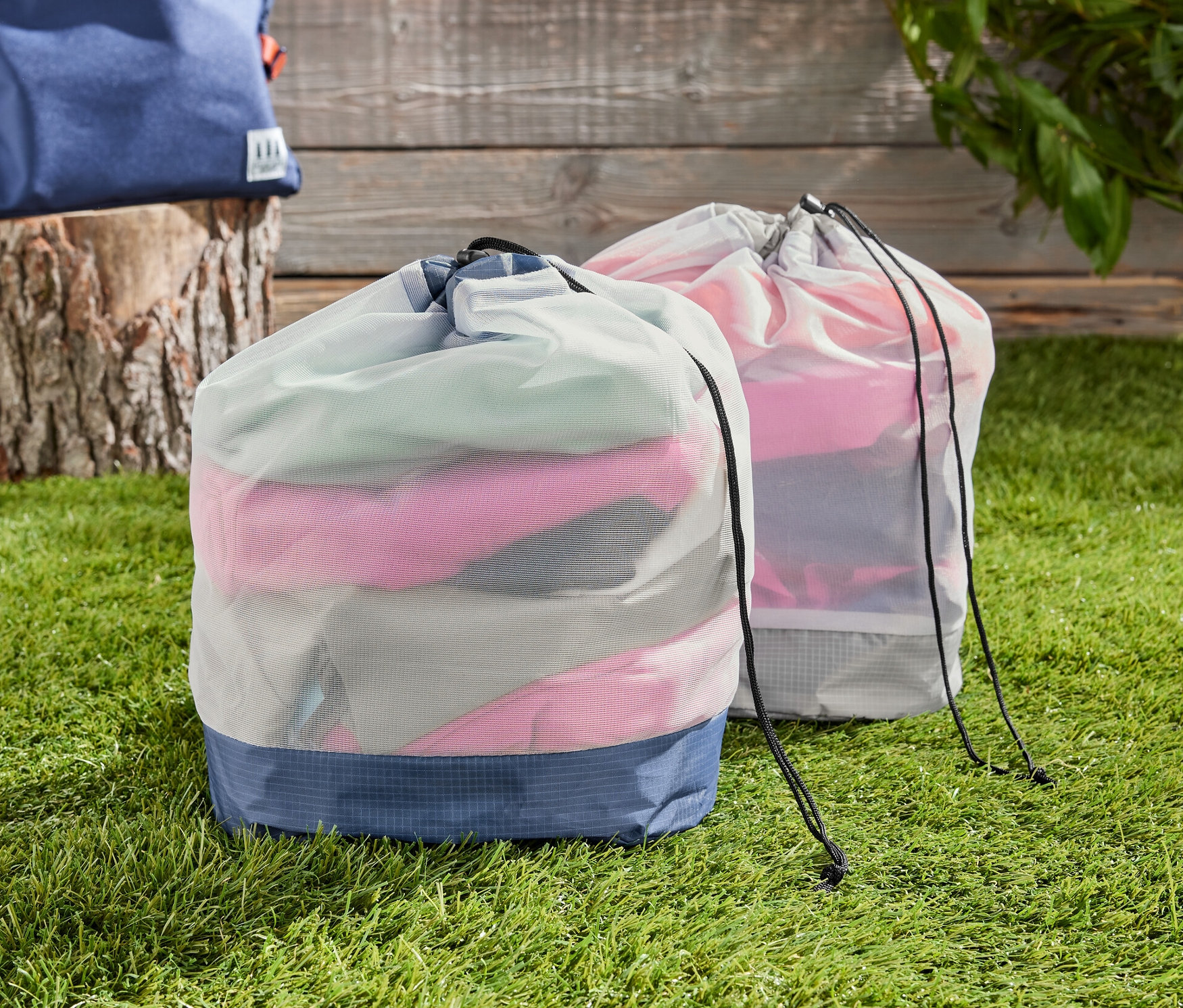 Deux sacs en filet pour l’extérieur sur l’herbe, un sac à dos en arrière-plan.