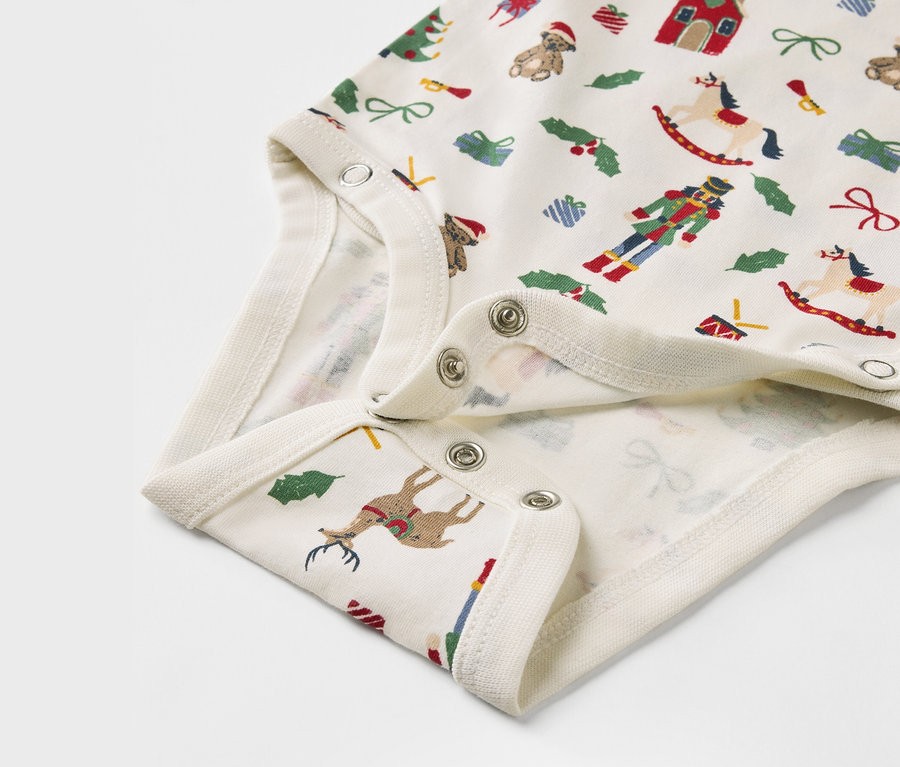 Détail d'un body pour bébé avec des motifs de Noël.