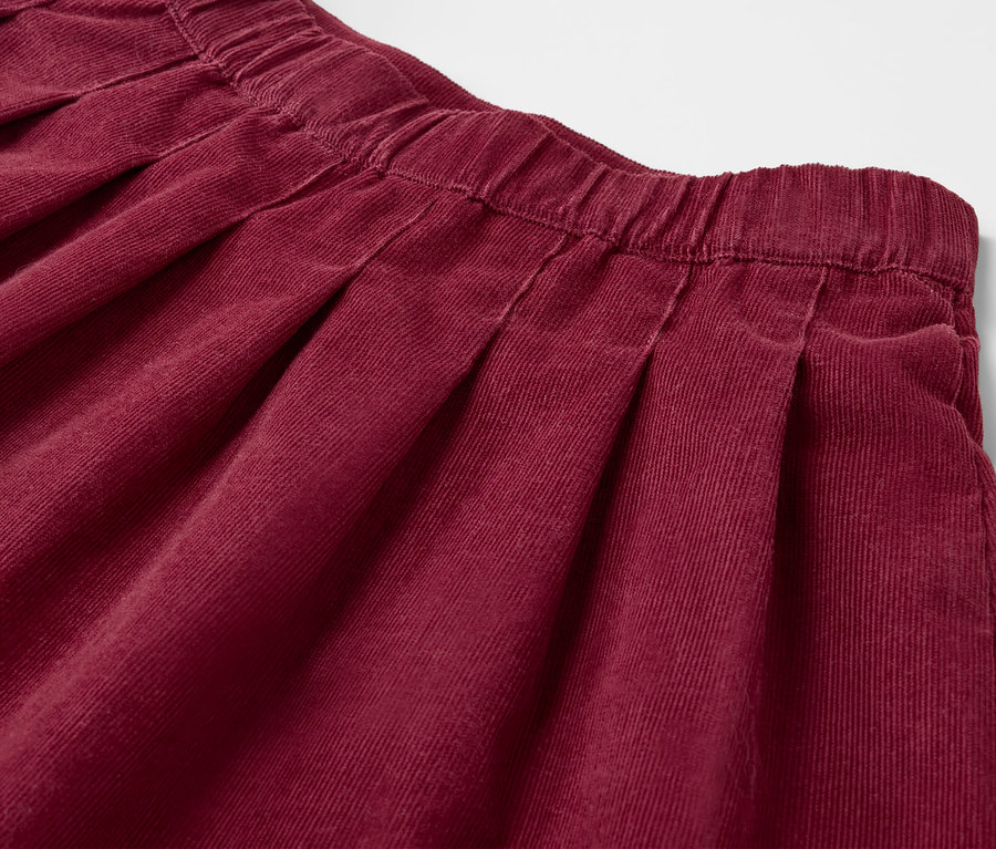 Détail d'une jupe plissée bordeaux pour enfant.