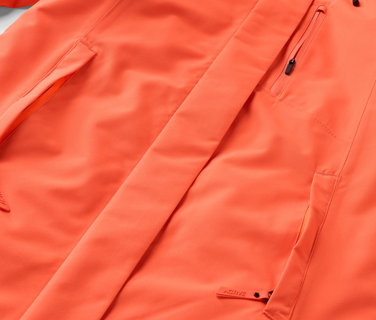 Détail d'une veste orange avec poches et fermeture éclair.