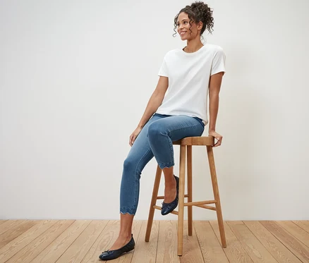Femme assise sur un tabouret portant un tregging 7/8 à broderie ajourée.