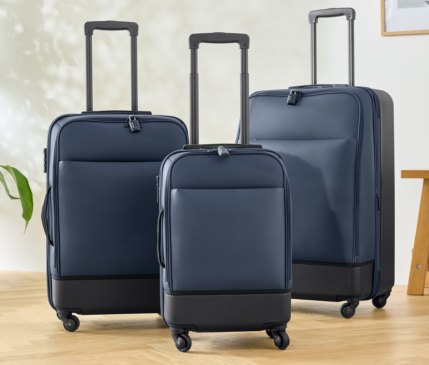 Trois valises hybrides (petite, moyenne et grande) sont posées sur un plancher en bois.