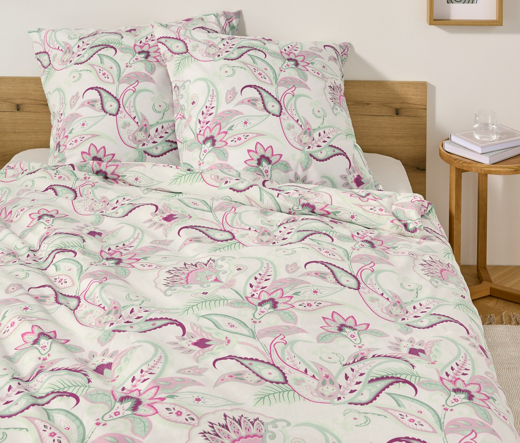 Lit avec parure de lit blanche en renforcé à motif cachemire et deux oreillers.