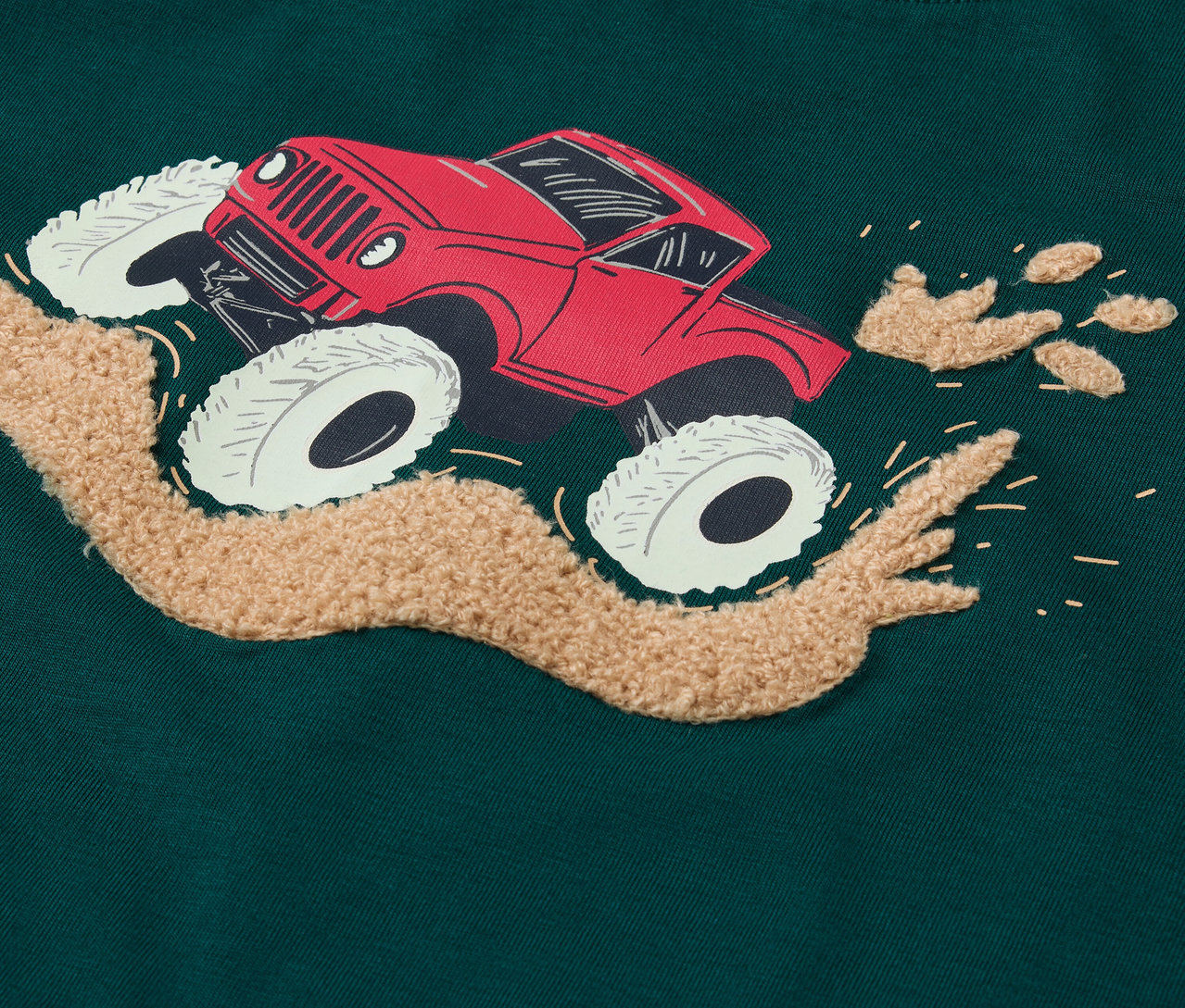 Gros plan sur un t-shirt vert avec un imprimé de camion rouge.