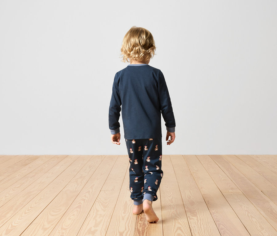 Garçon en pyjama bleu marine avec motif de lapin, de dos.