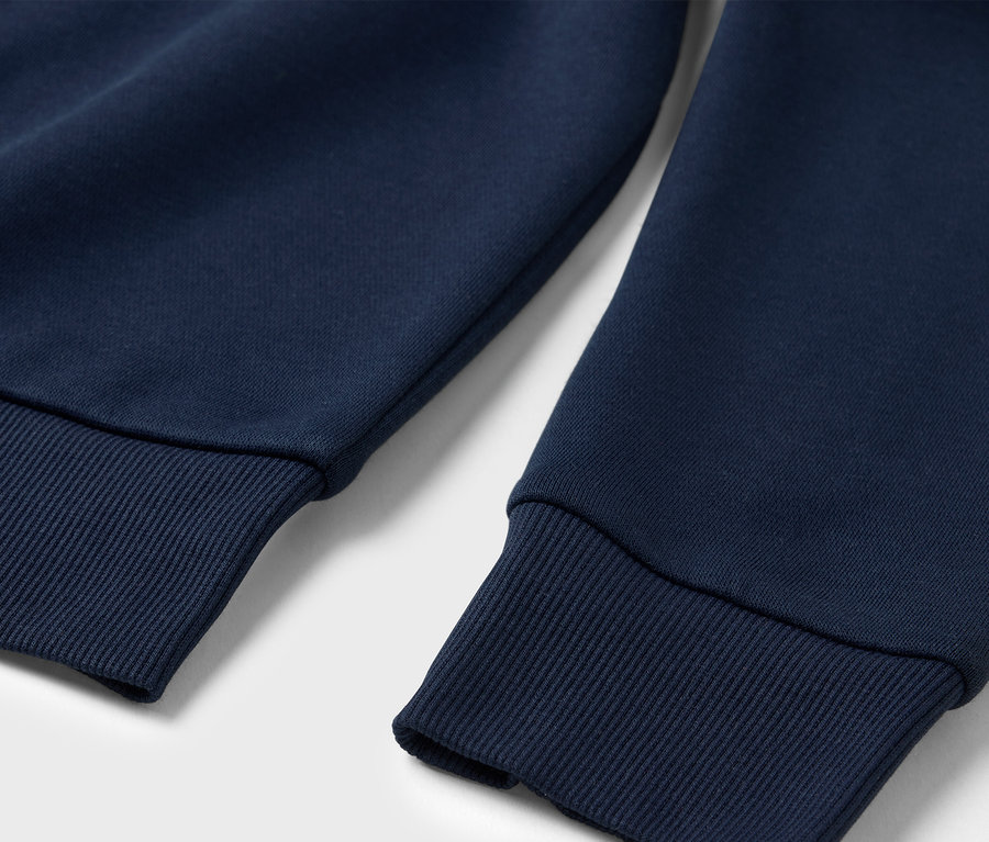 Gros plan sur un sweatshirt bleu marine avec des poignets côtelés.