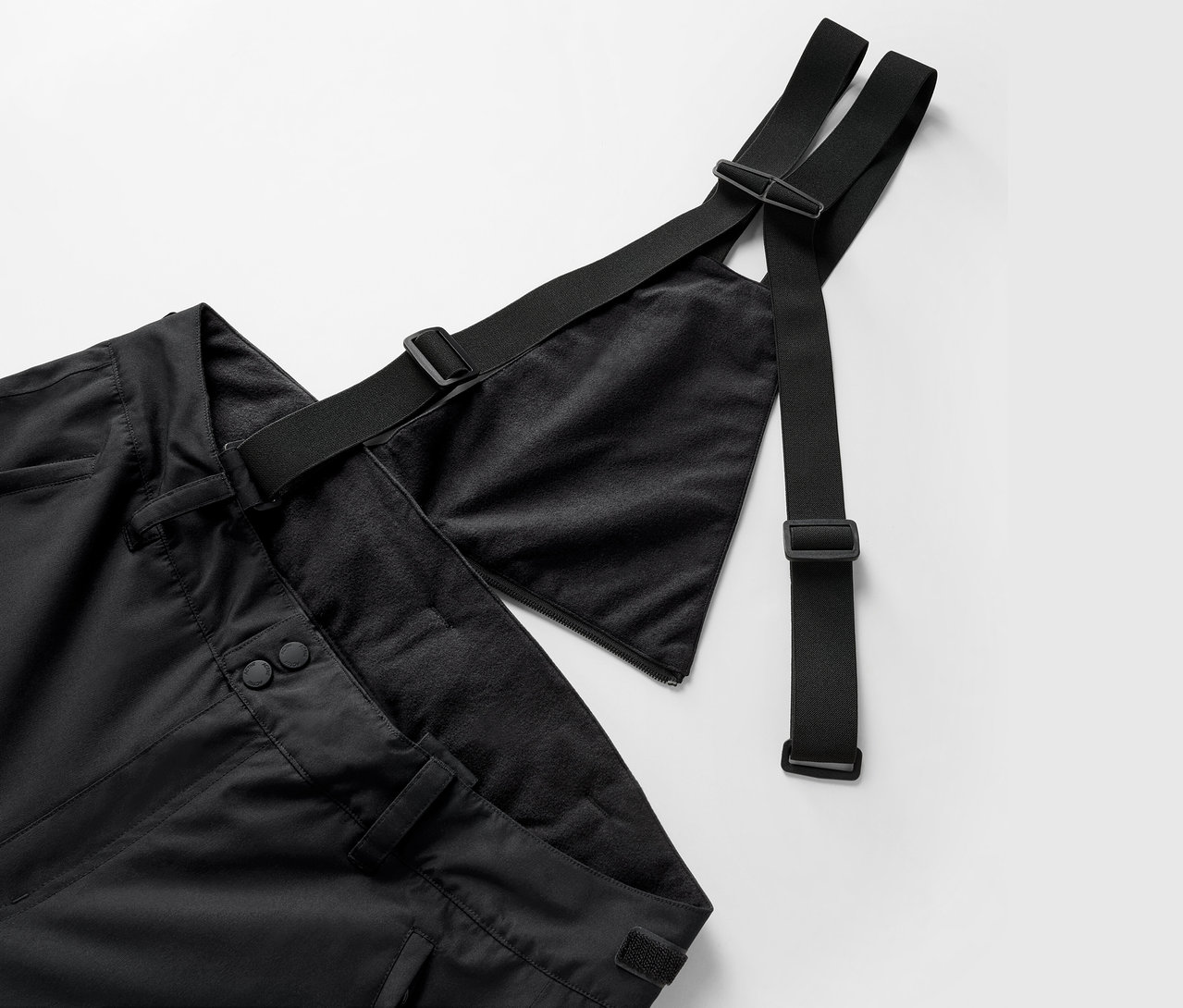 Gros plan sur un pantalon noir à bretelles et sangles réglables.