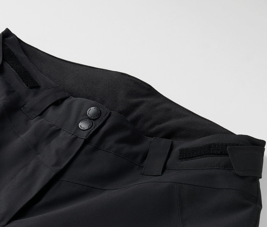 Gros plan sur un pantalon noir avec boutons et passants de ceinture.