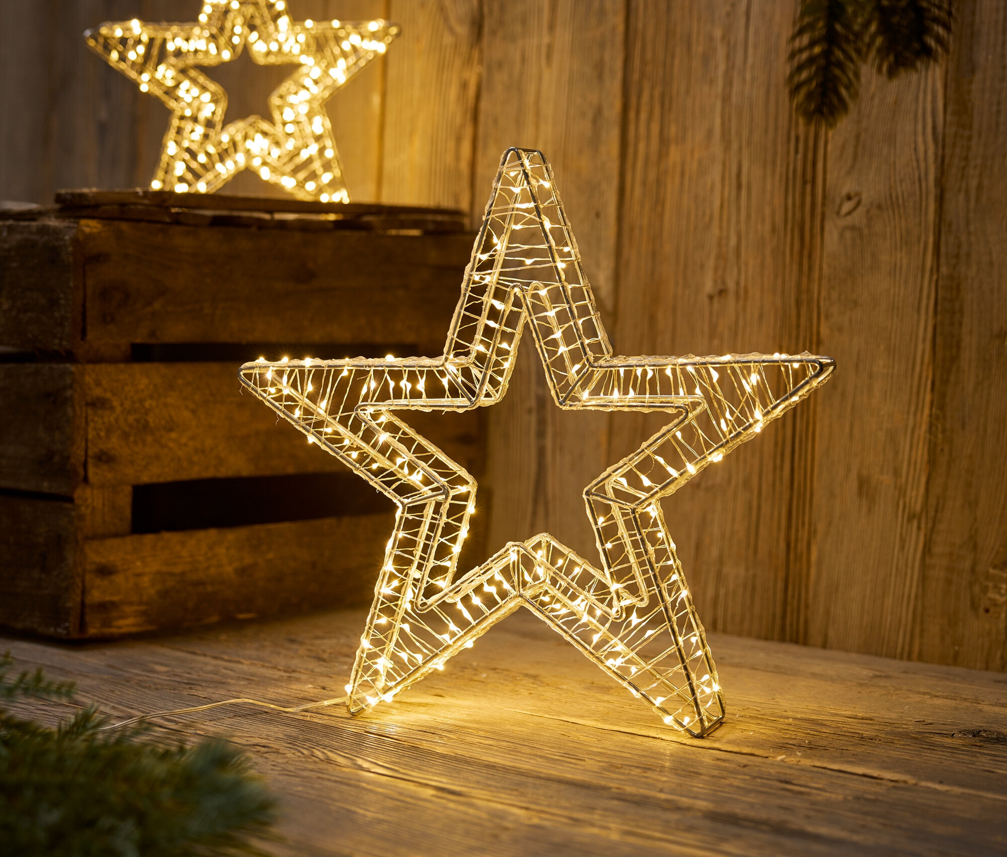 Deux étoiles décoratives avec des lumières LED sont posées sur une surface en bois.