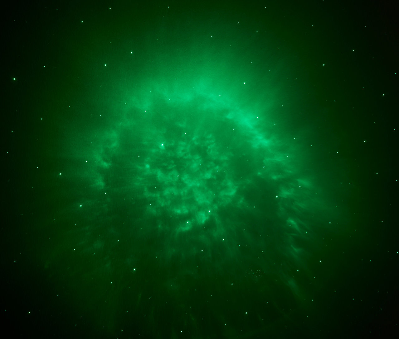 Nébuleuse verte avec des points lumineux sur un fond sombre.