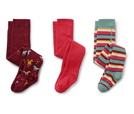 Sur un fond blanc, trois collants pour enfants : bordeaux avec des chevaux et des étoiles, rouge et rayé avec du turquoise, du rouge, du jaune et du blanc.