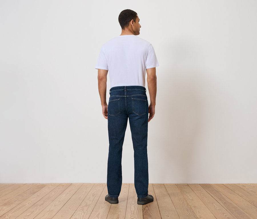 Un homme se tient dos à la caméra, portant un jean et un t-shirt.