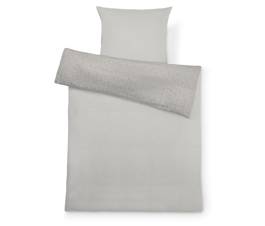 Linge de lit gris clair avec un oreiller et un long coussin à motif géométrique.