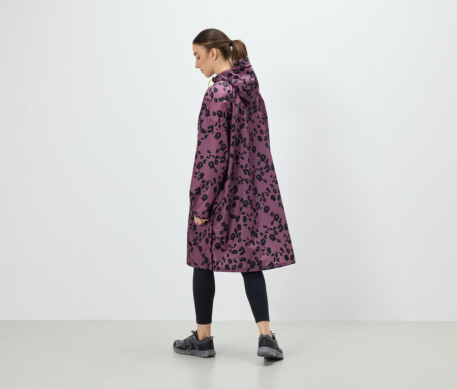 Une femme porte un manteau violet avec un imprimé animalier noir, un legging noir et des baskets grises.