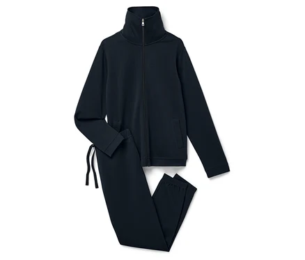 Un survêtement bleu marine composé d'une veste zippée et d'un pantalon posé sur un fond blanc.