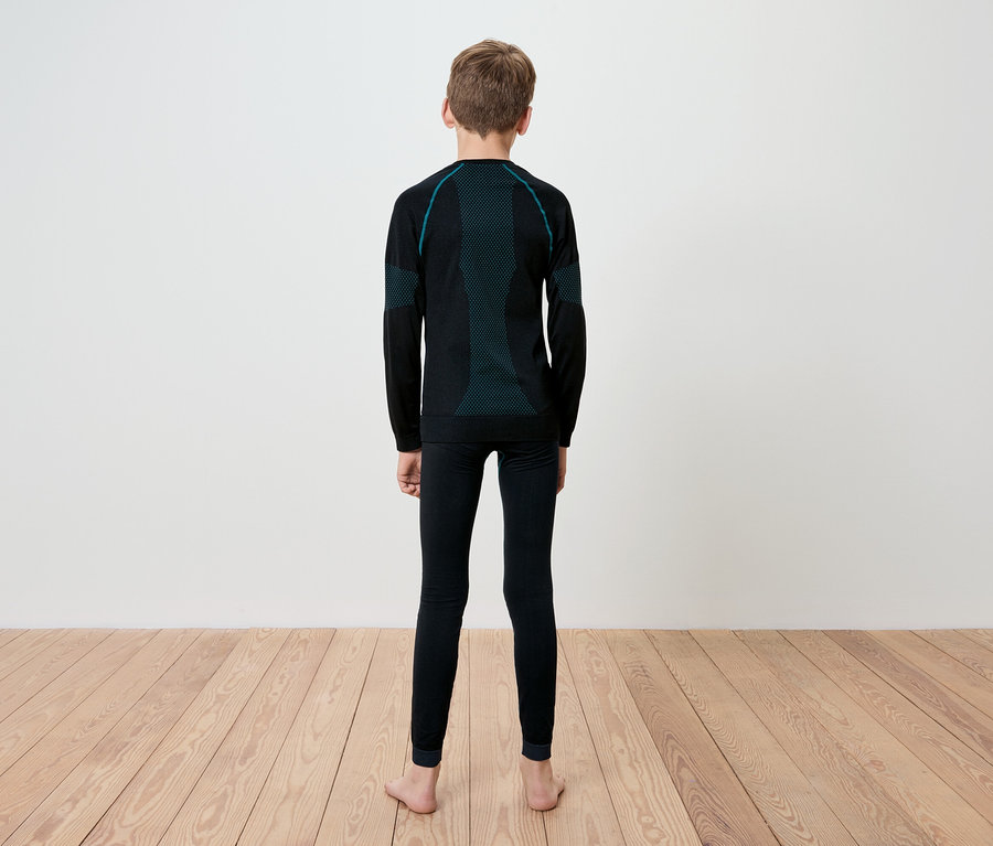 Un garçon, vu de dos, porte des sous-vêtements thermiques noirs à manches longues et des leggings avec des détails turquoise.