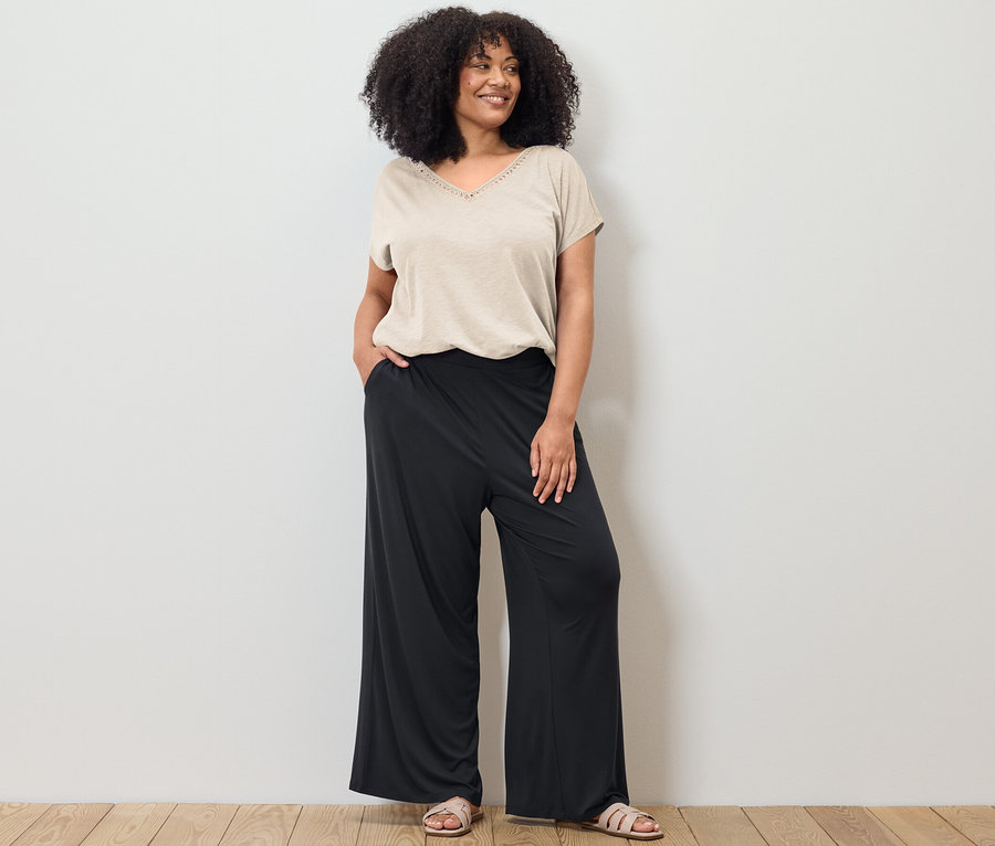 Femme posant dans un t-shirt en mélange avec modal blanc crème et un pantalon palazzo noir.