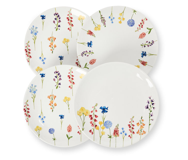 Quatre assiettes à dessert décorées de fleurs sont posées les unes sur les autres.