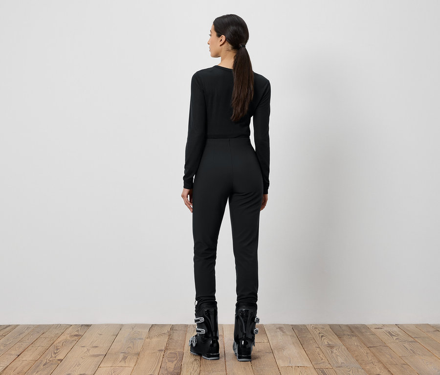 Femme en tenue de ski noire, de dos.