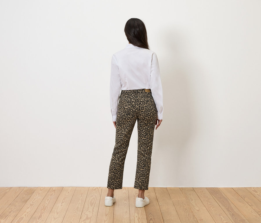 Vue arrière d'une femme portant une chemise blanche et un pantalon à imprimé léopard.