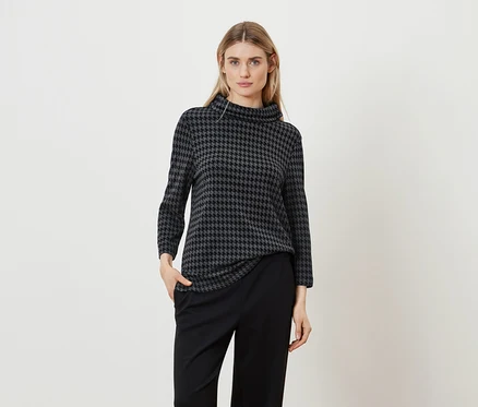 Femme posant dans un haut à motif pied-de-poule et un pantalon noir.