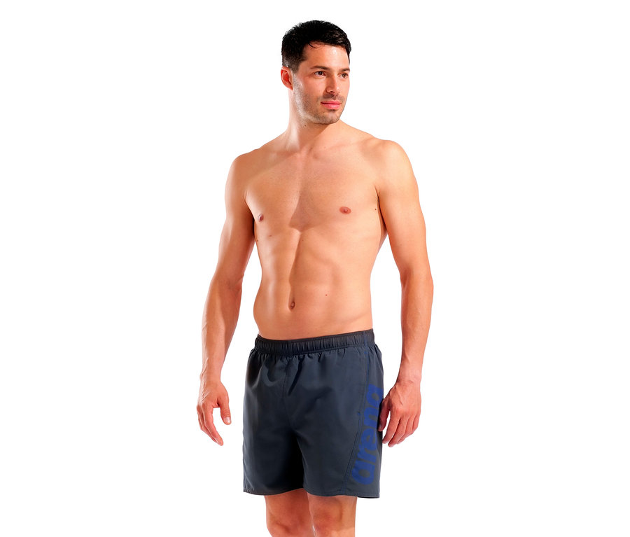 Homme torse nu portant un short de bain gris avec l'inscription ARENA en bleu.