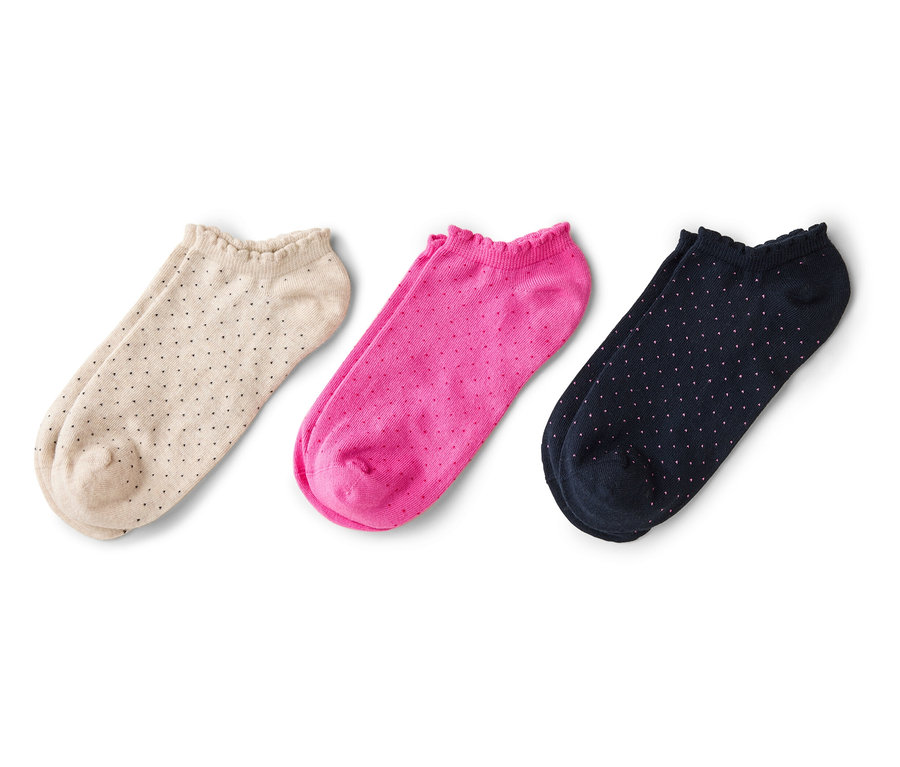 Trois paires de chaussettes basses, beige à pois noirs, rose et bleu marine à pois blancs, posées sur un fond blanc.