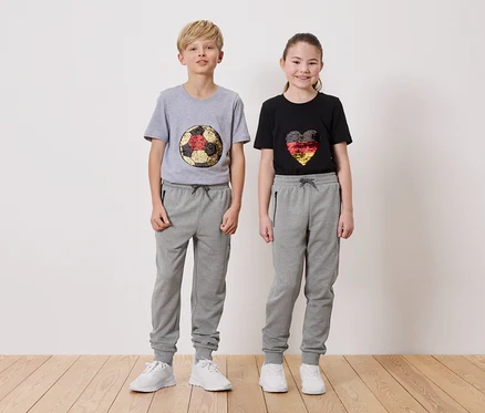 Un garçon portant un t-shirt gris avec un motif de ballon de football et une fille portant un t-shirt noir avec un motif de cœur, tous deux portant des pantalons de survêtement gris.