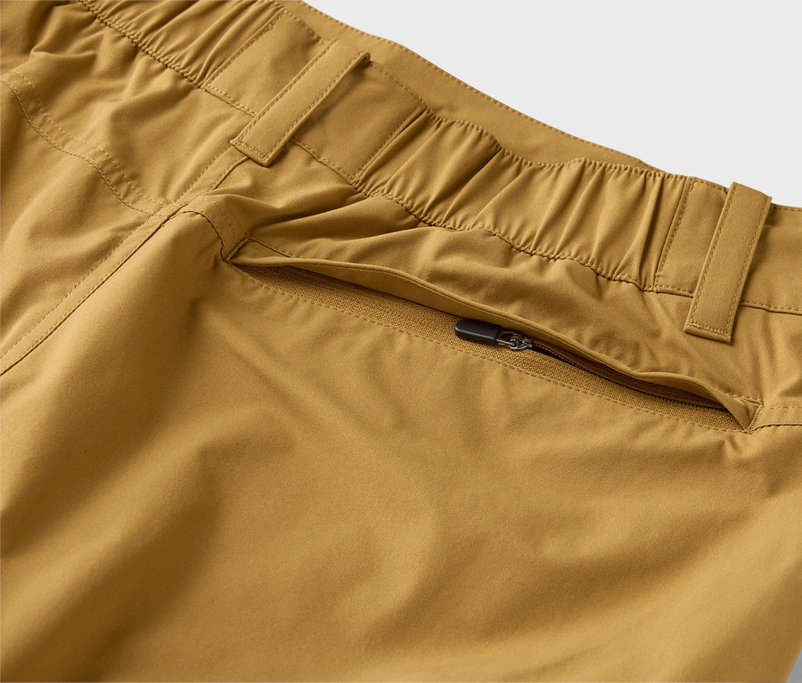 Gros plan d'un pantalon kaki avec une taille élastique et une poche zippée.