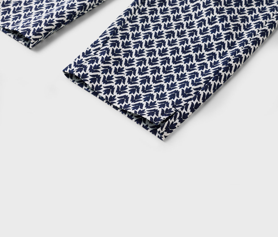 Gros plan sur le bas des jambes d'un pantalon avec un motif de feuilles bleu et blanc.