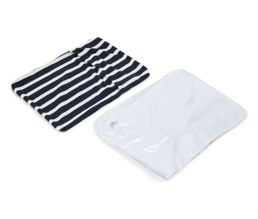 Un vêtement rayé bleu marine et blanc et un sac sous vide blanc sont posés sur un fond blanc.