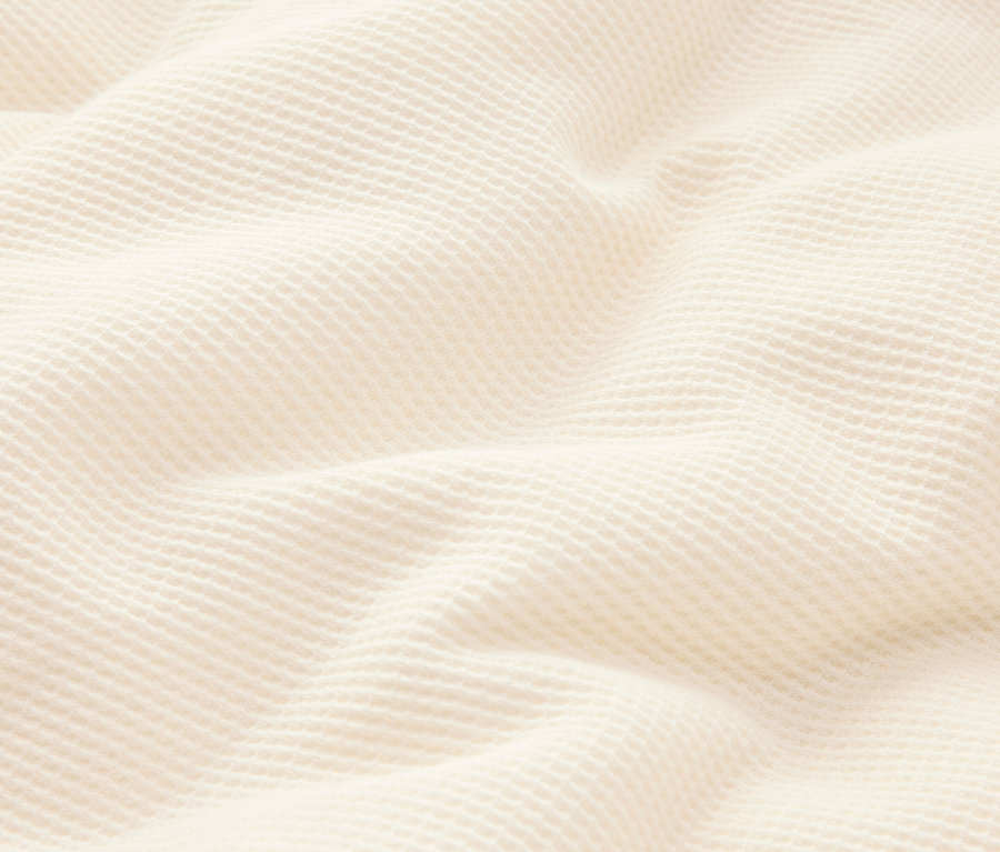 Gros plan d'un tissu gaufré crème ondulé.