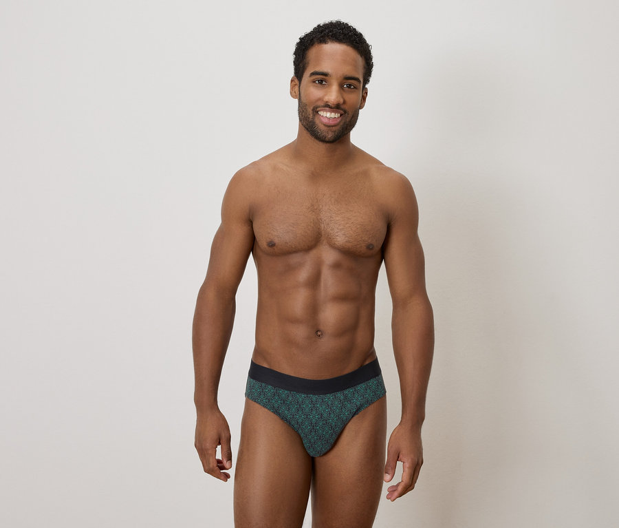 Homme à la peau foncée portant des slips pour hommes à motifs et souriant.