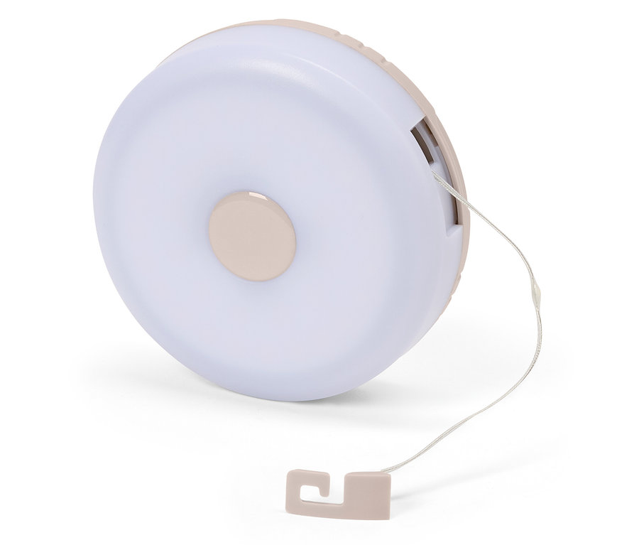 Gros plan d'une lampe de chevet ronde rose clair avec cordon sur fond blanc.