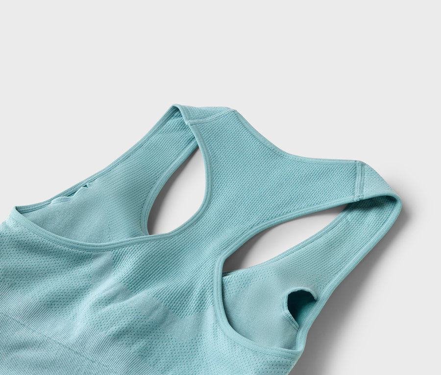 Gros plan d'un soutien-gorge de sport turquoise clair avec un dos nageur sur un fond blanc.