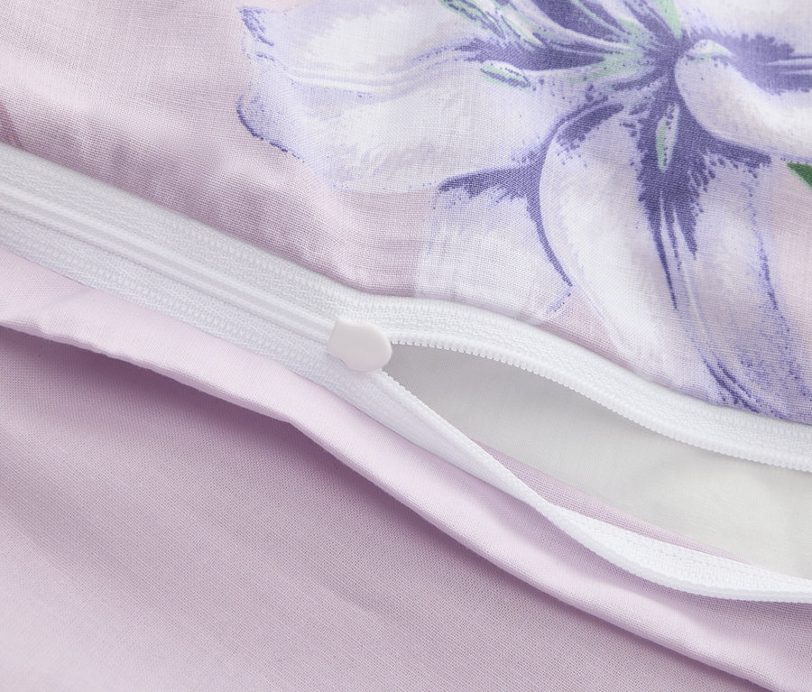 Gros plan d'une housse de couette violette partiellement ouverte avec un imprimé floral et une fermeture éclair.