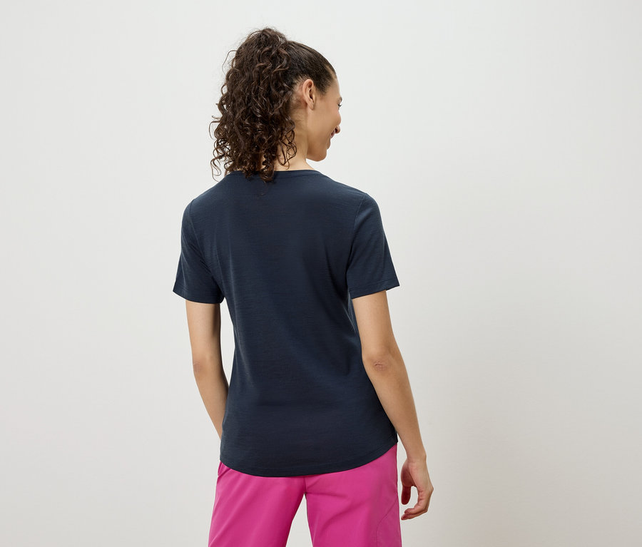 Vue arrière d'une femme aux cheveux bouclés portant un t-shirt bleu marine et un short rose.