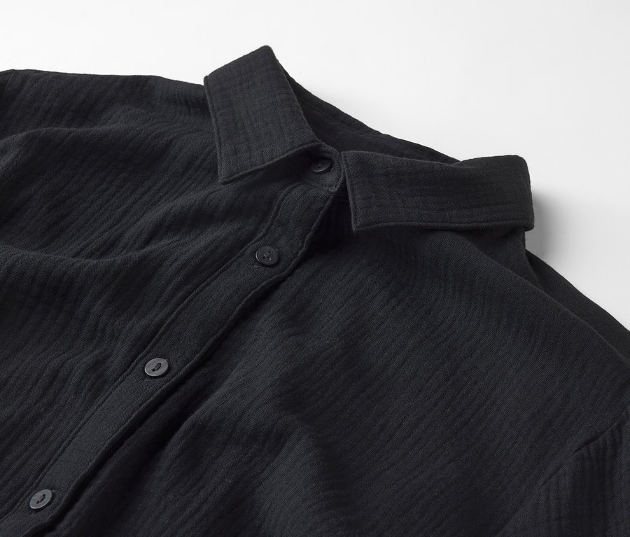 Vue détaillée d'une chemise noire avec col et boutons.