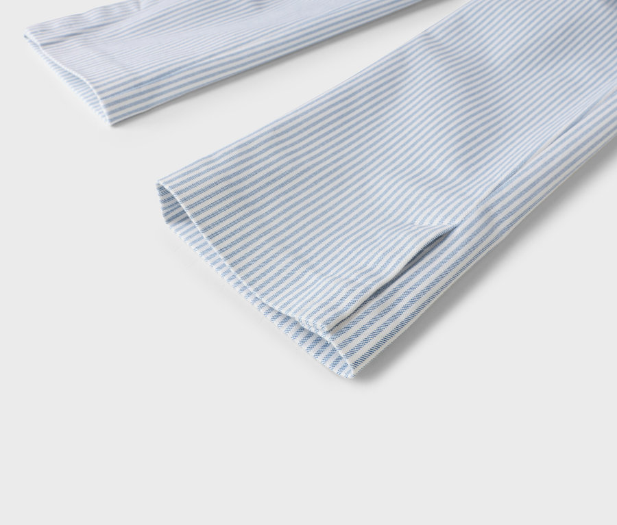 Vue détaillée de deux manches de chemise à rayures bleu clair et blanches sur fond gris clair.