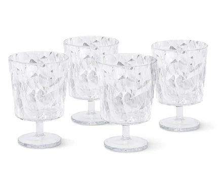 Quatre verres à vin vides et transparents avec un motif à facettes se tiennent sur un fond blanc.