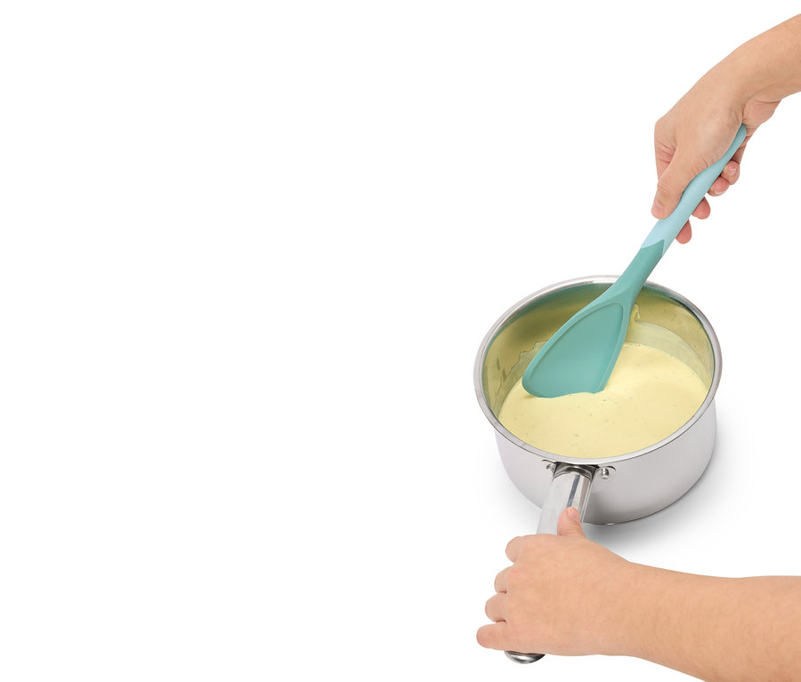 Une personne mélange un liquide jaune dans une casserole avec une spatule turquoise.