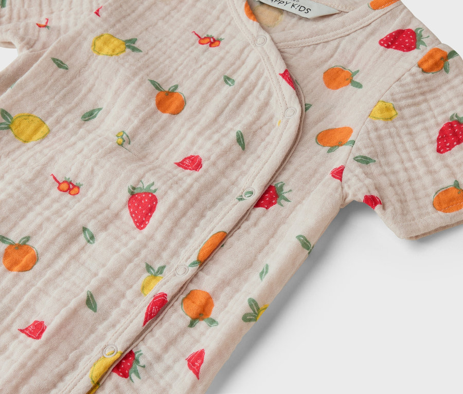 Gros plan sur un pyjama bébé rose clair avec des motifs de fruits.
