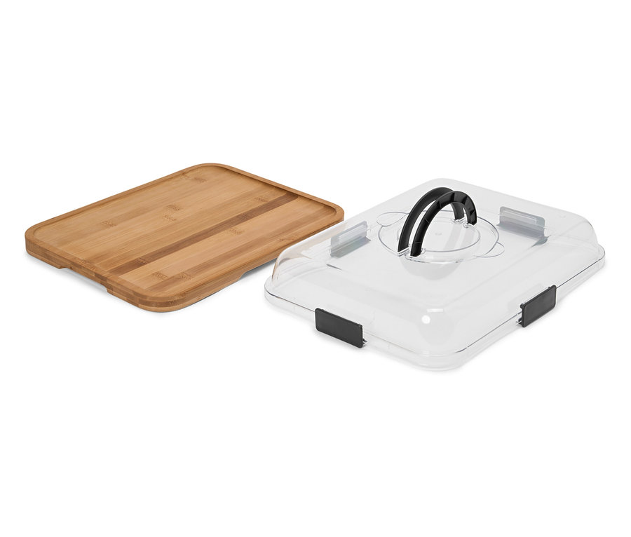 Une planche à découper rectangulaire en bois est posée à côté d'un couvercle rectangulaire transparent avec une poignée noire.