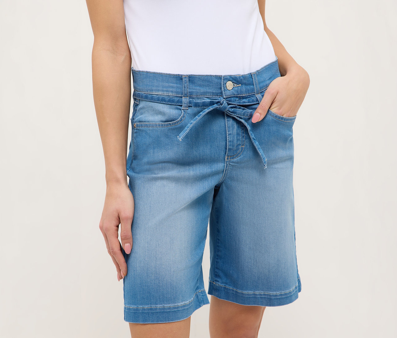 Femme portant un short Angels Denim «
Lia City
», bleu clair, avec une ceinture à nouer et les mains dans les poches.