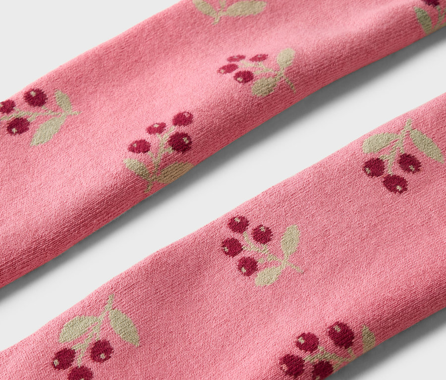 Gros plan de deux chaussettes roses avec un motif de baies rouges et de feuilles.