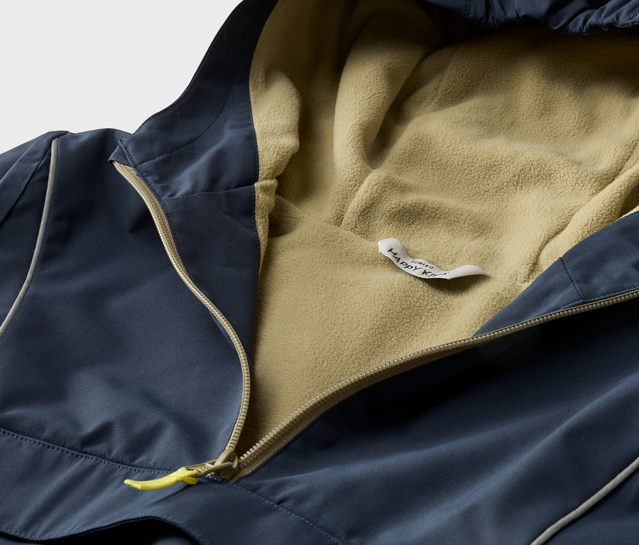 Gros plan d'un anorak à capuche bleu marine avec une fermeture éclair jaune et une doublure en polaire beige.