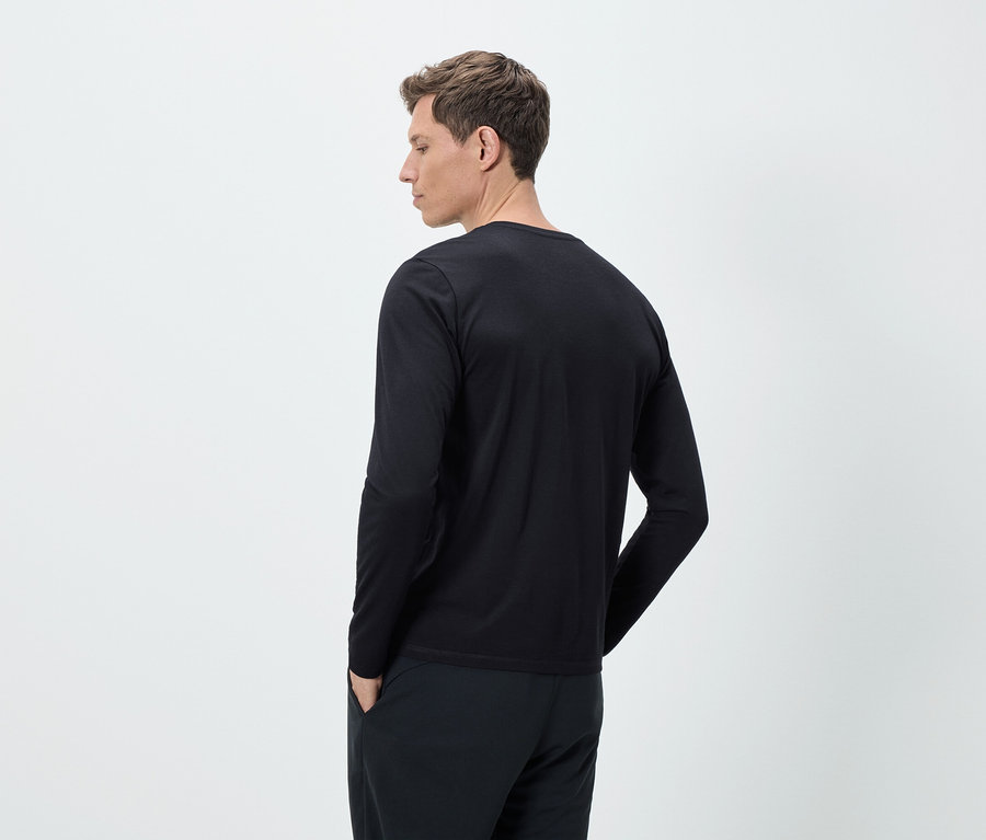 Homme vu de dos portant un t-shirt à manches longues et un pantalon noirs.